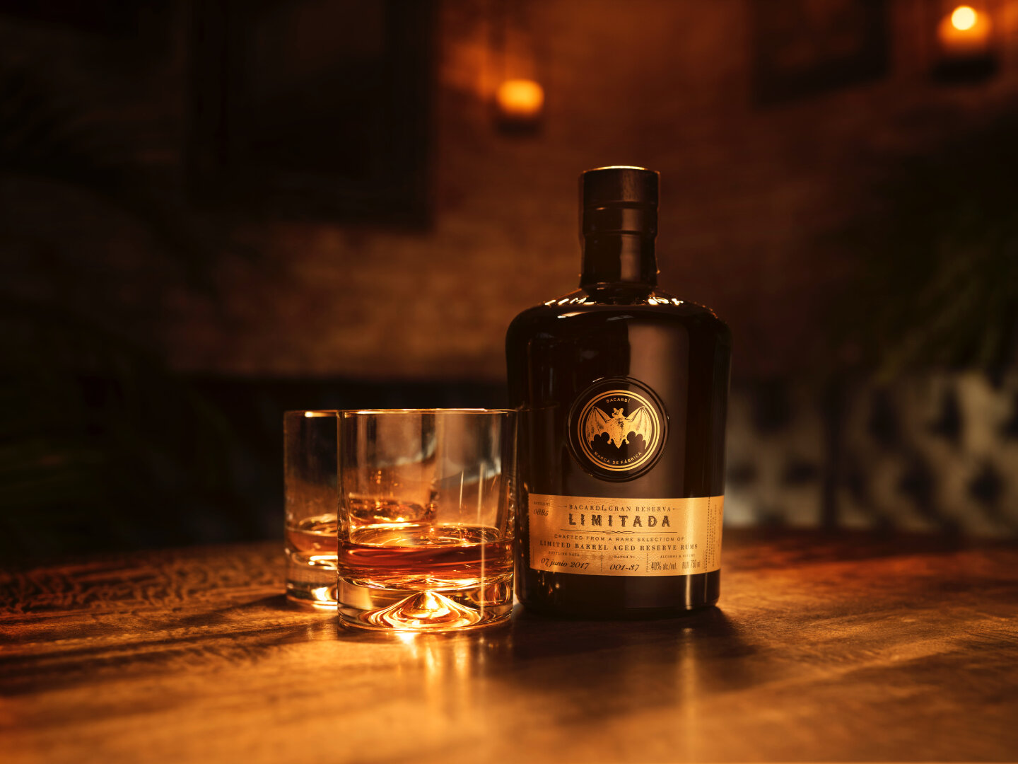 BACARDÍ Limitada rum bottle with two short glasses, one filled with amber rum.