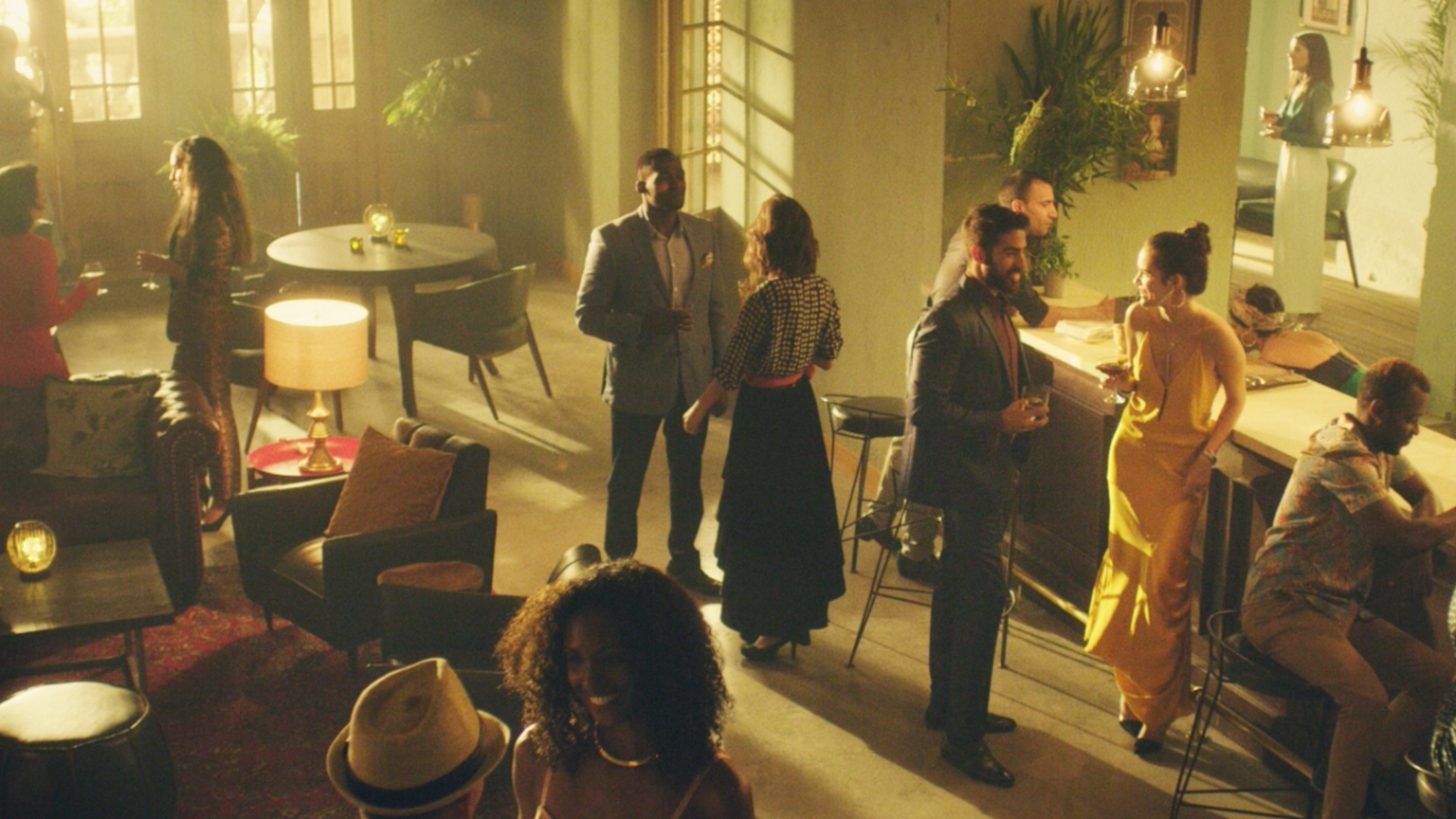 People socializing in a dimly lit lounge with mid-century modern furniture and soft ambient lighting.