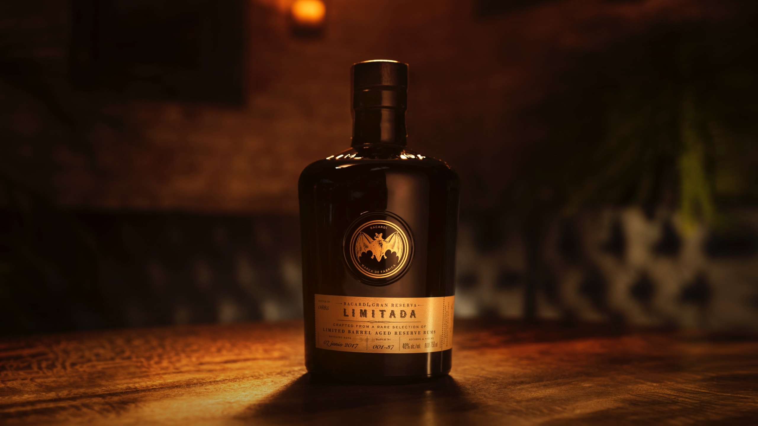 Dark BACARDÍ rum bottle with gold label and prominent bat logo.