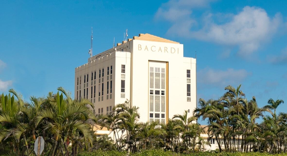 Large BACARDÍ corporate building with palm trees under bright blue sky.