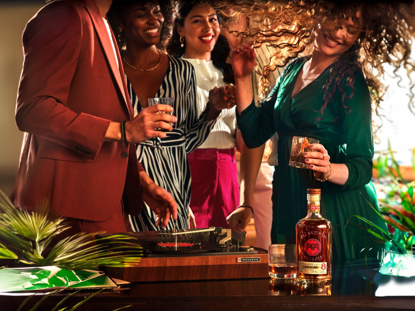 Social gathering with BACARDÍ Reserva 8 rum bottle, people enjoying music near turntable.