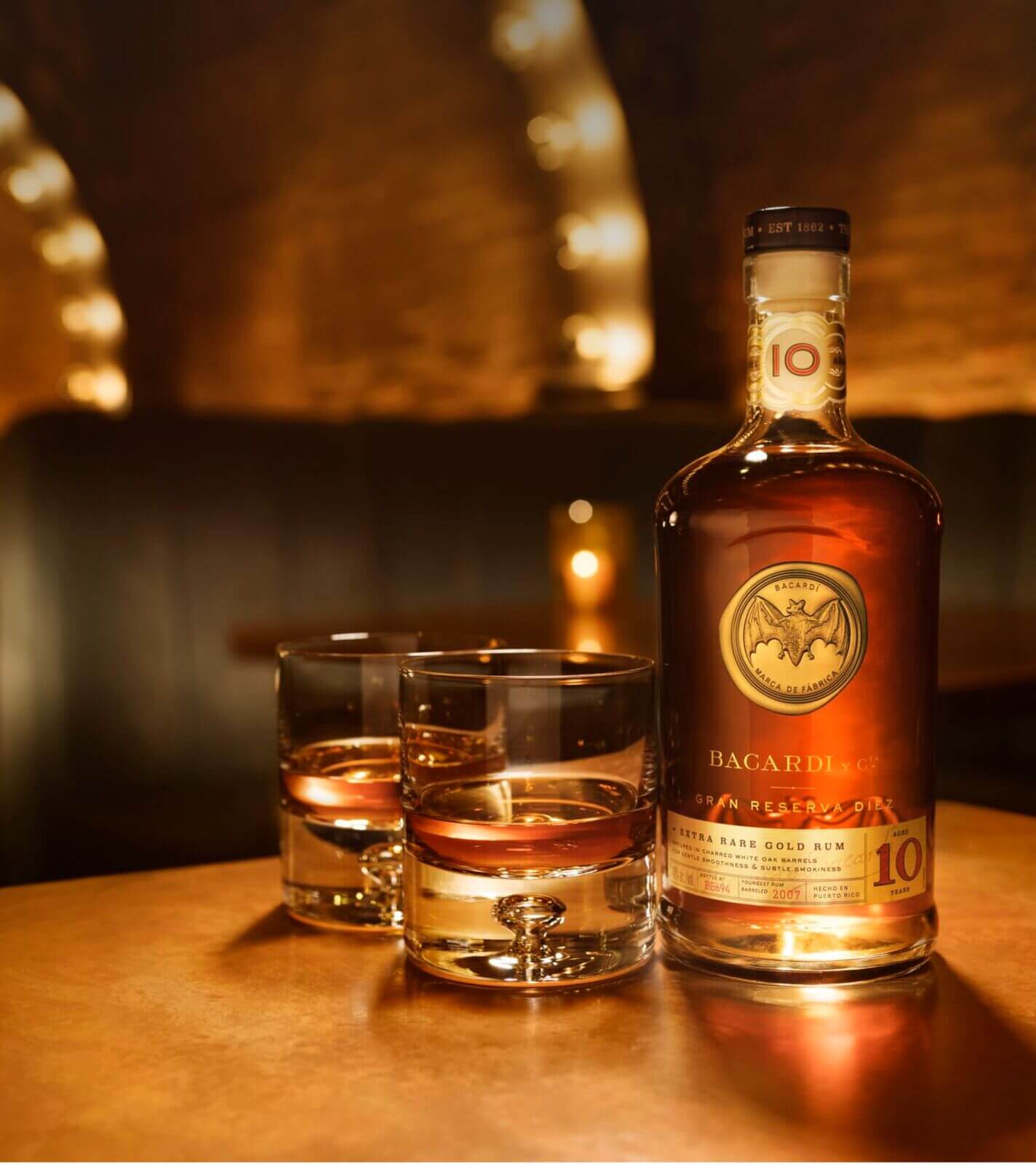 BACARDÍ Gran Reserva Diez rum bottle with two accompanying glasses of amber liquid.