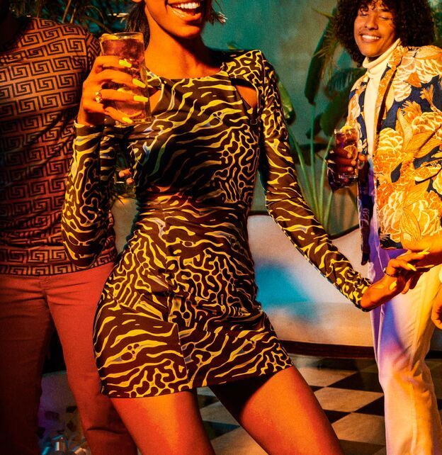 People at a social gathering, holding drinks in a lively setting.