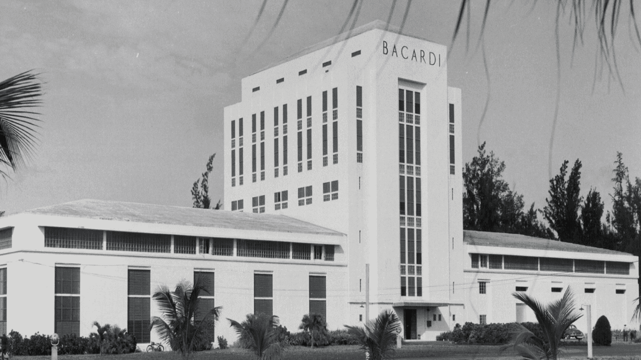 Black and white photograph of white Art Deco BACARDÍ building with palm trees in the foreground.