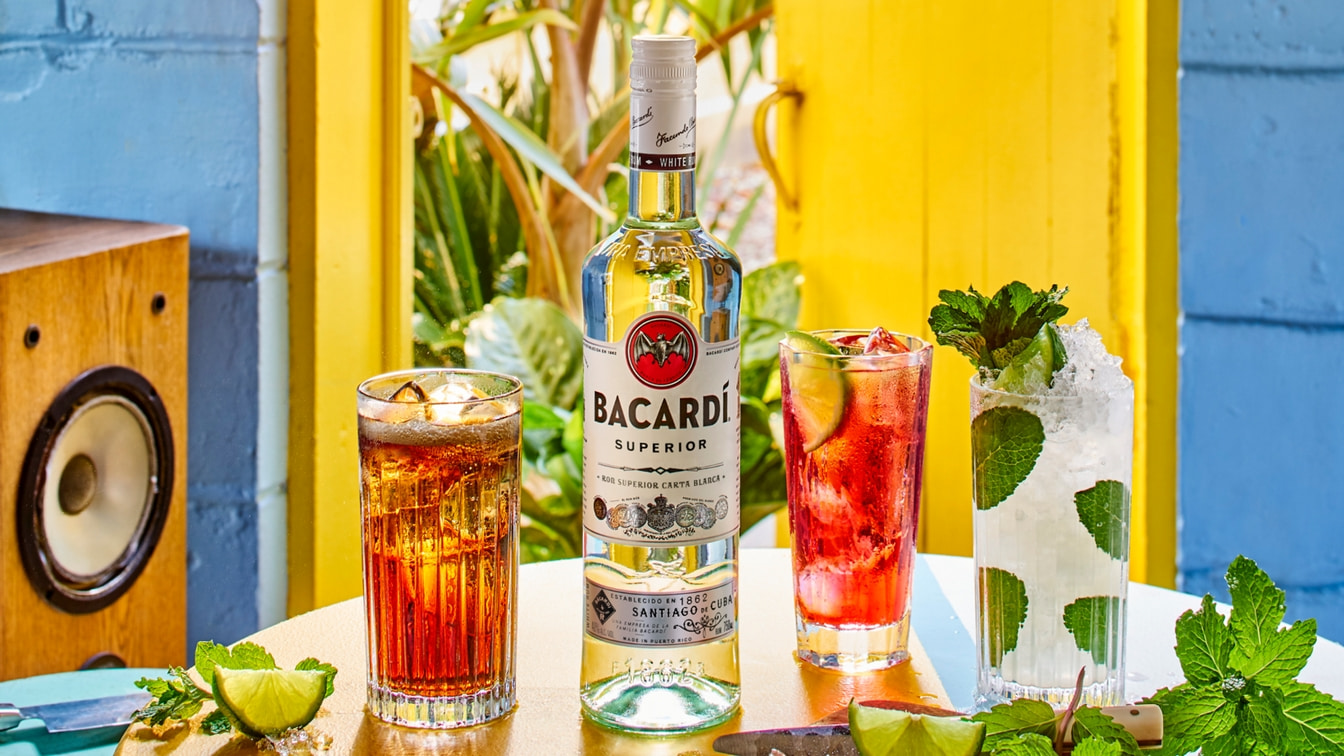 BACARDÍ Superior rum bottle centered among three colorful cocktails, with vintage speaker nearby.