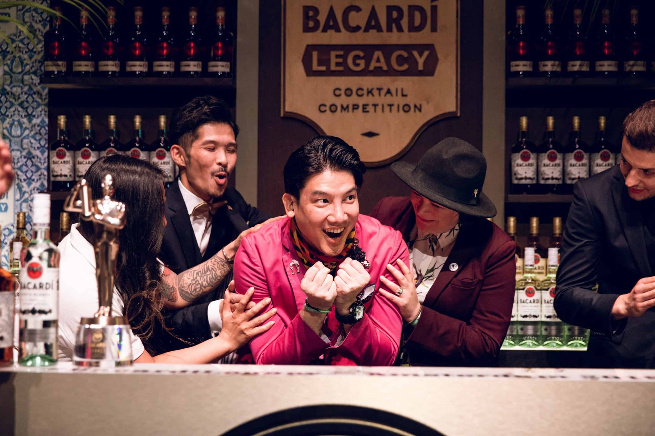 Excited participant at Bacardí Legacy Cocktail Competition standing with clenched fists near competition signage.