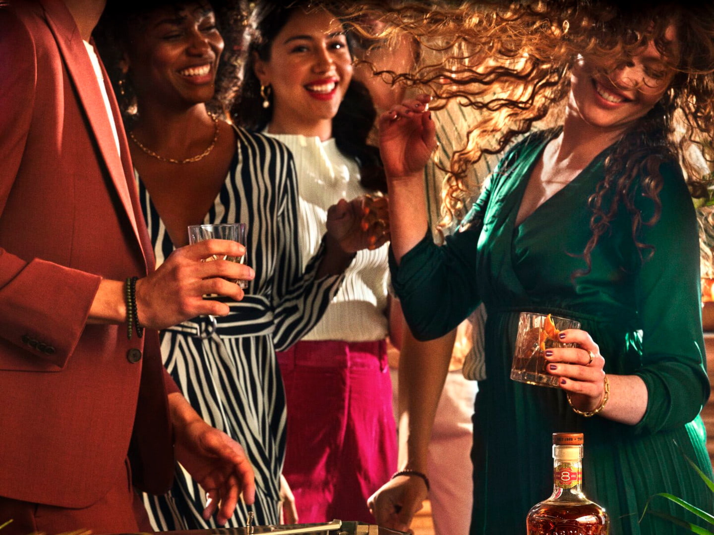Group of people enjoying a social gathering with a BACARDÍ 8 rum bottle in the foreground.