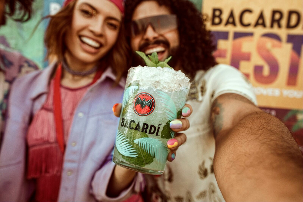Mojito cocktail in branded glass with crushed ice, fresh mint, held in a selfie-style pose.