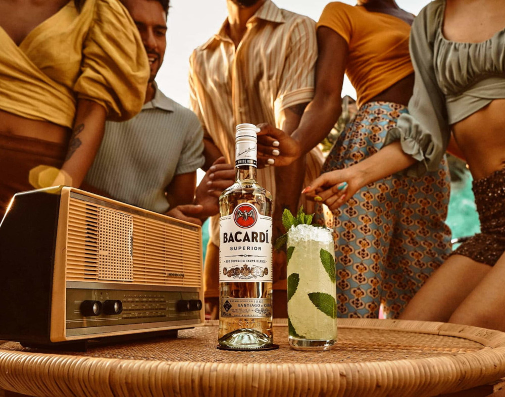 Bacardí Superior rum bottle, tall mojito with mint leaves, crushed ice near vintage radio.