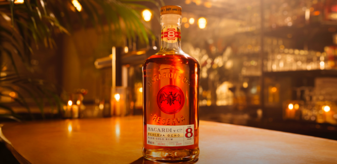 Bacardí Reserva Ocho rum bottle positioned centrally with palm leaves framing the composition.