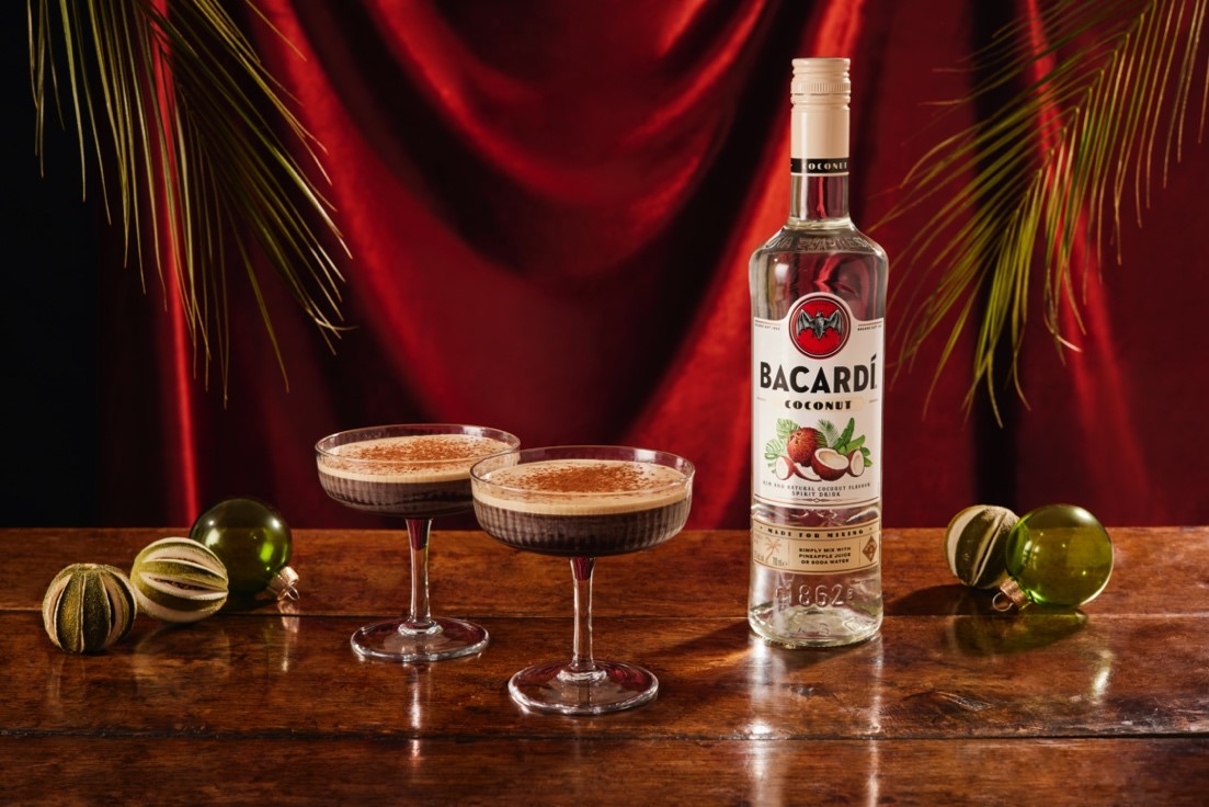 Bacardí Coconut rum bottle with two espresso martinis, Christmas baubles, dried citrus slices.