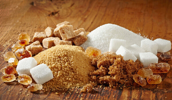 Close-up of sugar varieties including white, light brown, dark brown granulated sugar, cubes, crystals.