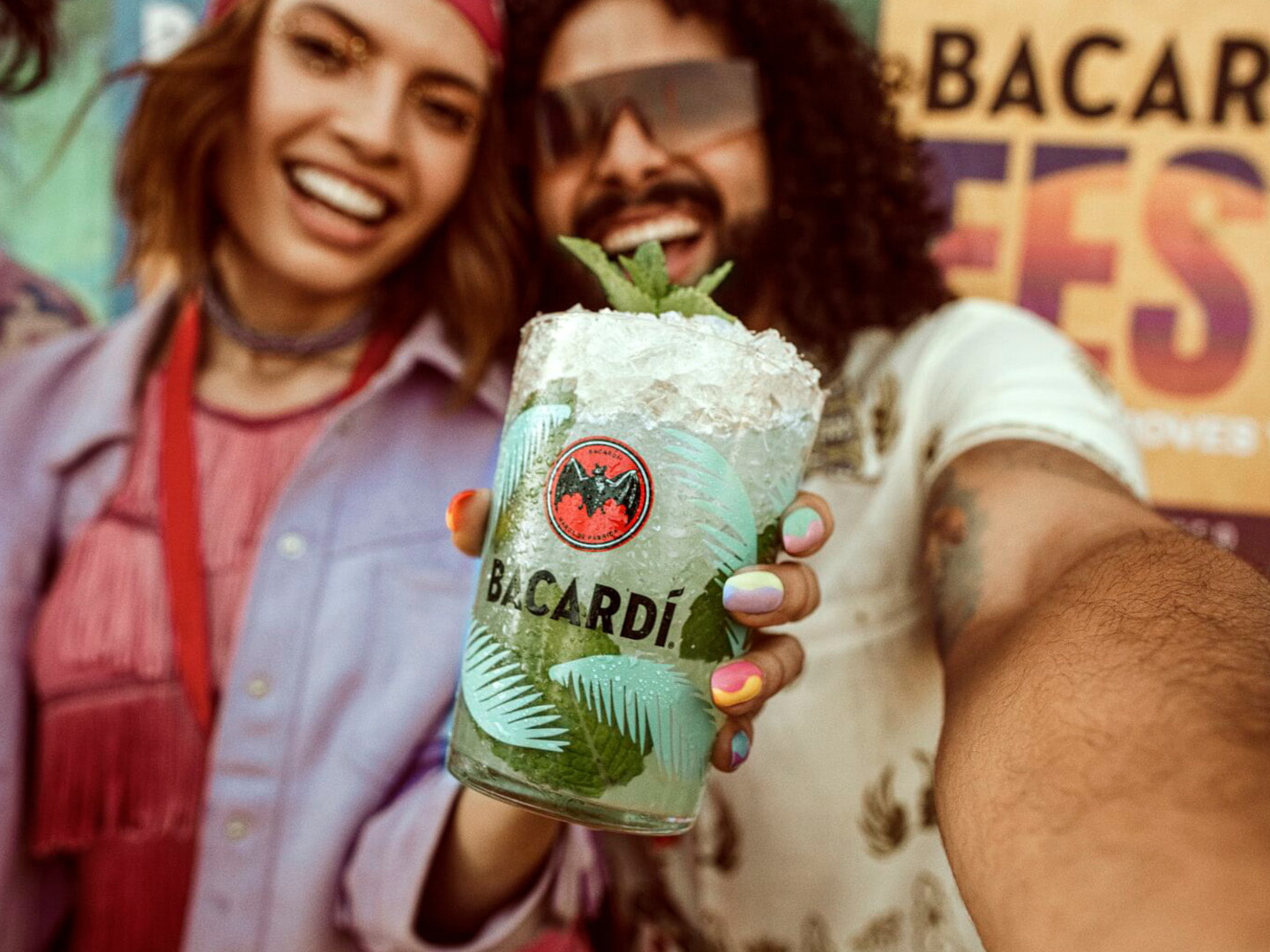 Person holding a cocktail in a glass with BACARDÍ logo.