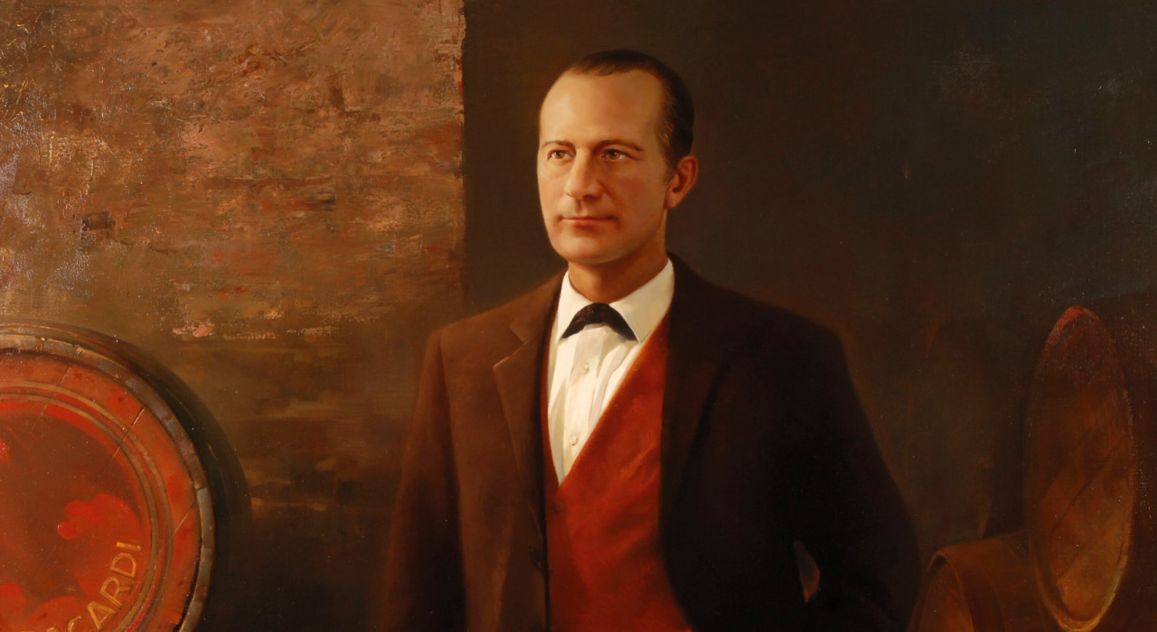 Painted portrait of a man in brown suit, white shirt, red vest, positioned between two rum barrels.