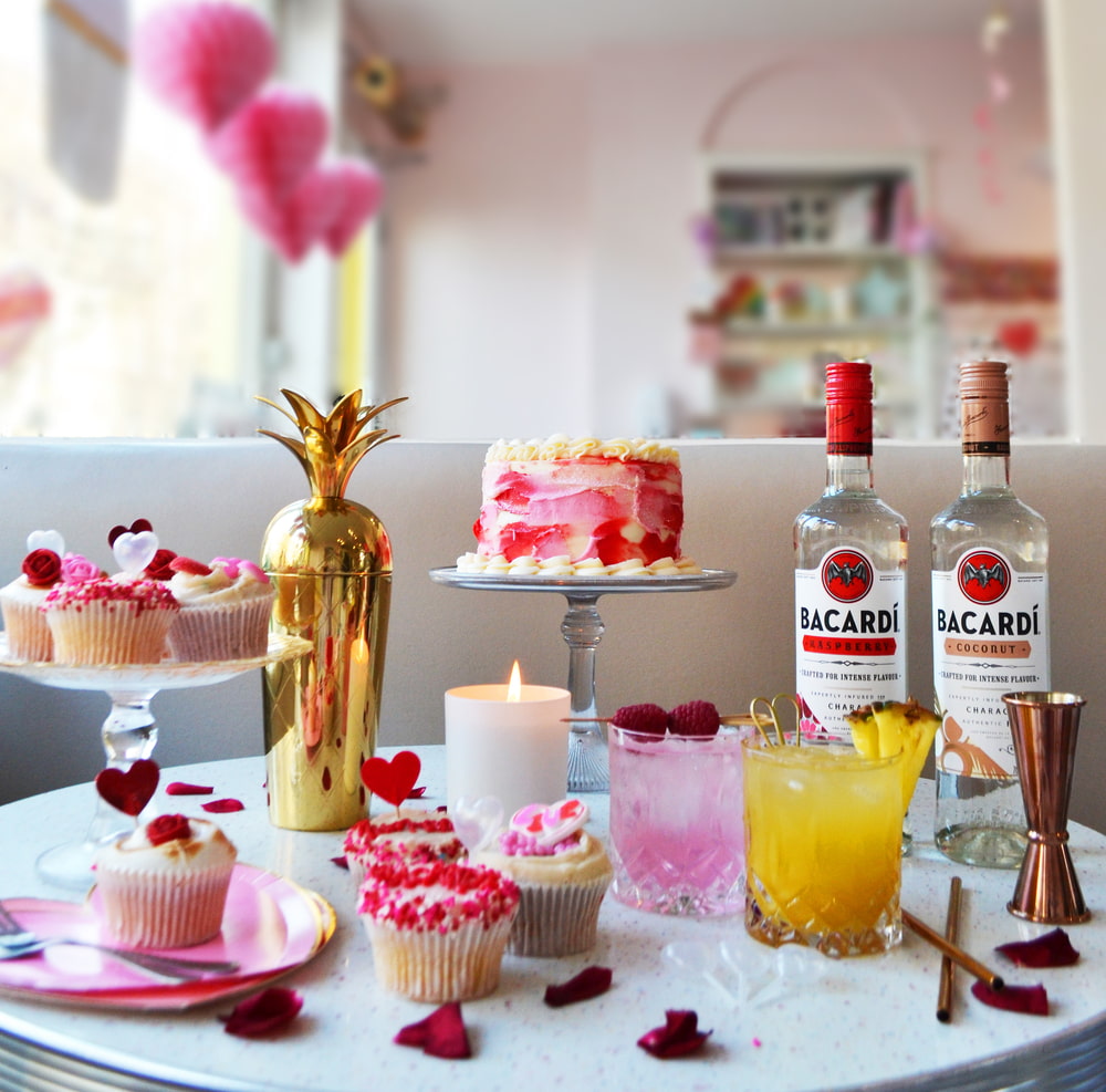 Valentine's Day table with BACARDÍ rum bottles, pink cocktails, cake, cupcakes, gold shaker.