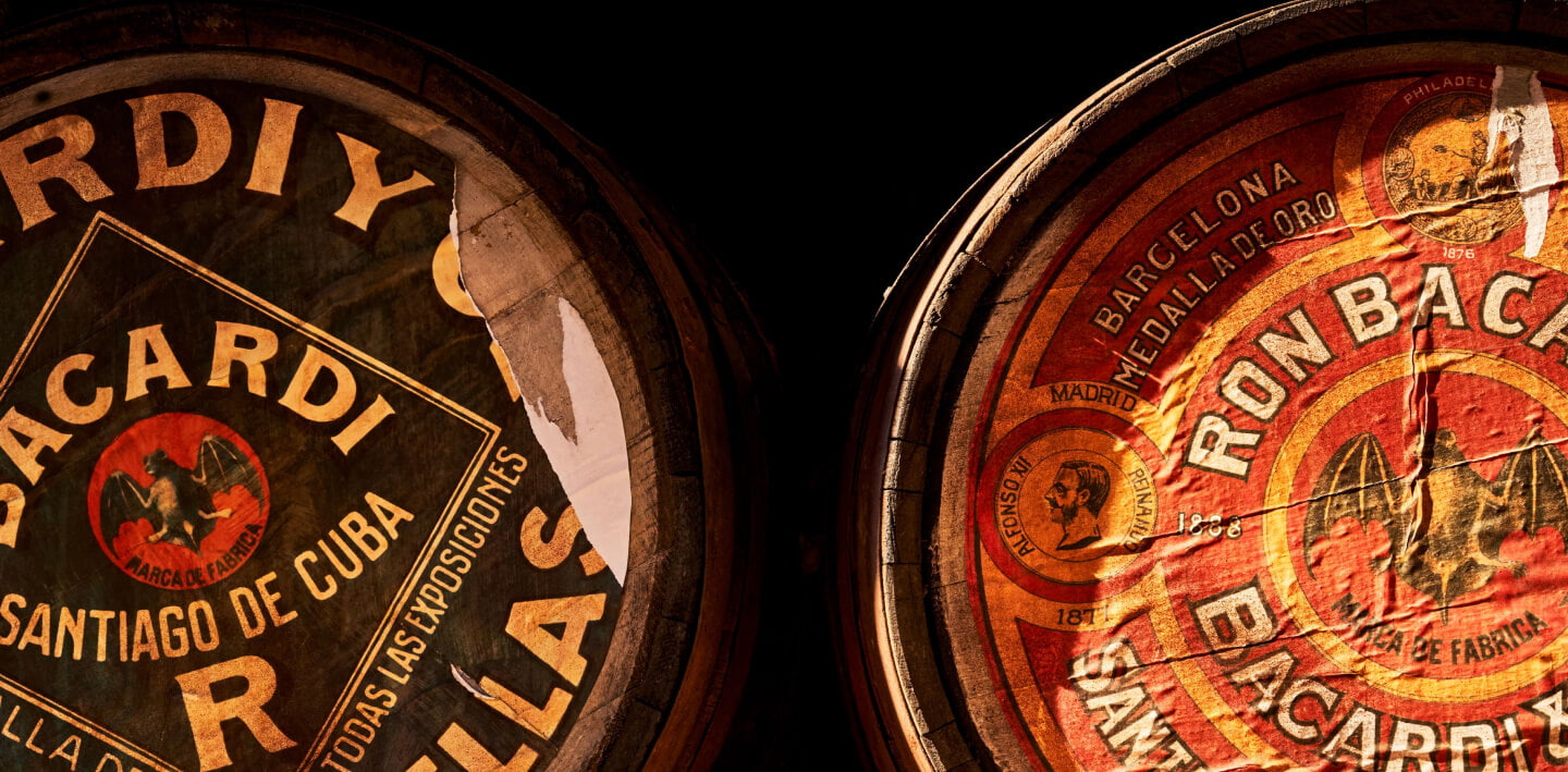 Close-up of two vintage wooden BACARDÍ rum barrels with worn, historic labels.