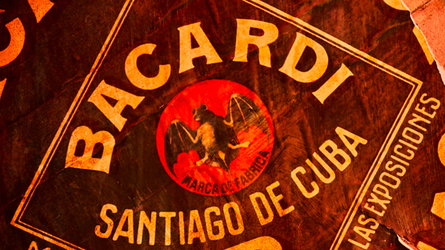 Close-up of vintage BACARDÍ logo with red circle, black bat, and cream-colored text.