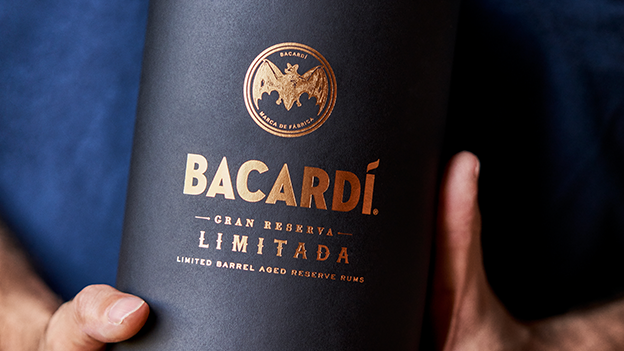 Close-up of hands holding BACARDÍ Gran Reserva Limitada rum packaging with gold foil lettering.