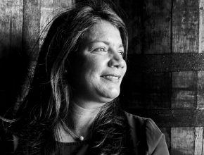 Black and white portrait of a person looking off-camera with a smile.