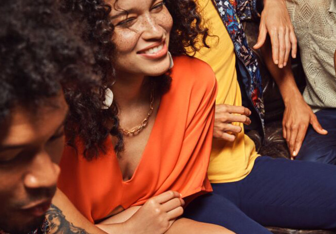 Close-up of people socializing at a gathering, with individuals wearing bright orange and yellow shirts.