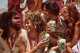 Friends holding BACARDÍ Mojito cocktails at an outdoor festival under bright sunlight.