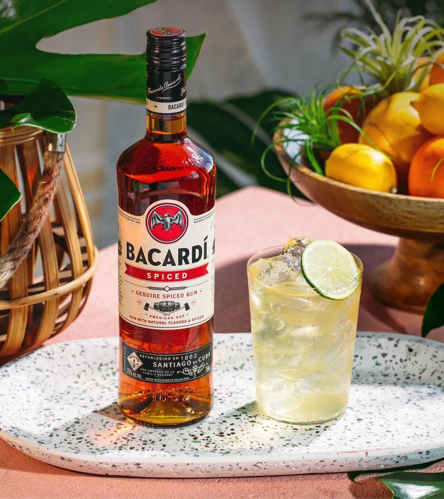 BACARDÍ Spiced rum bottle with cocktail glass, lime slice, ice cubes.