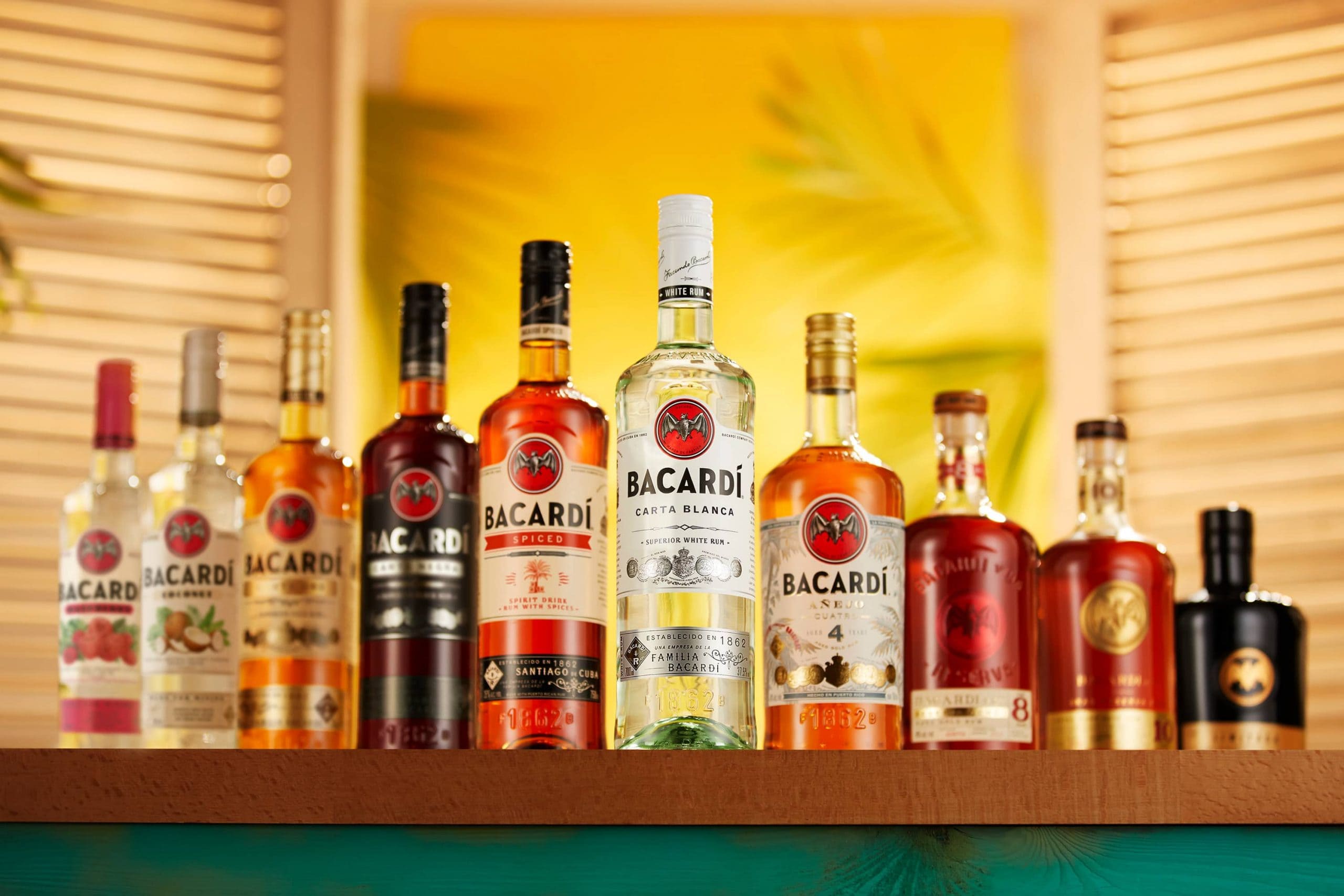 Multiple BACARDÍ rum bottles displayed in various colors and label designs.