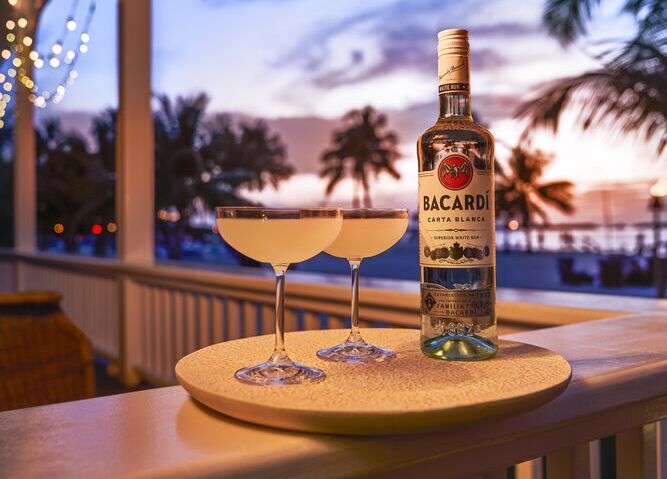 BACARDÍ Carta Blanca rum bottle next to two daiquiri cocktails.