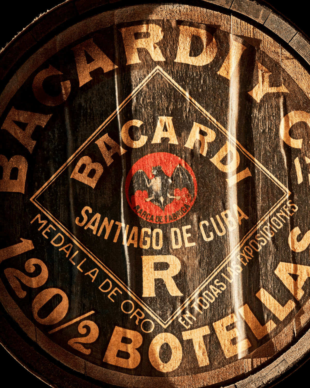 Wooden barrel head with BACARDÍ logo, bat symbol in red circle, branded text.