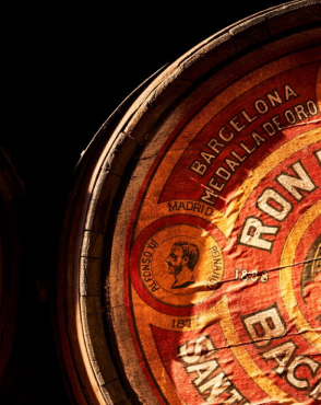 Vintage wooden rum barrel head with weathered red and gold label featuring BACARDÍ text.
