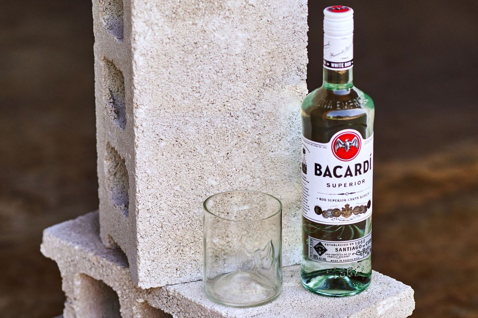 BACARDÍ Superior rum bottle standing next to an empty glass.