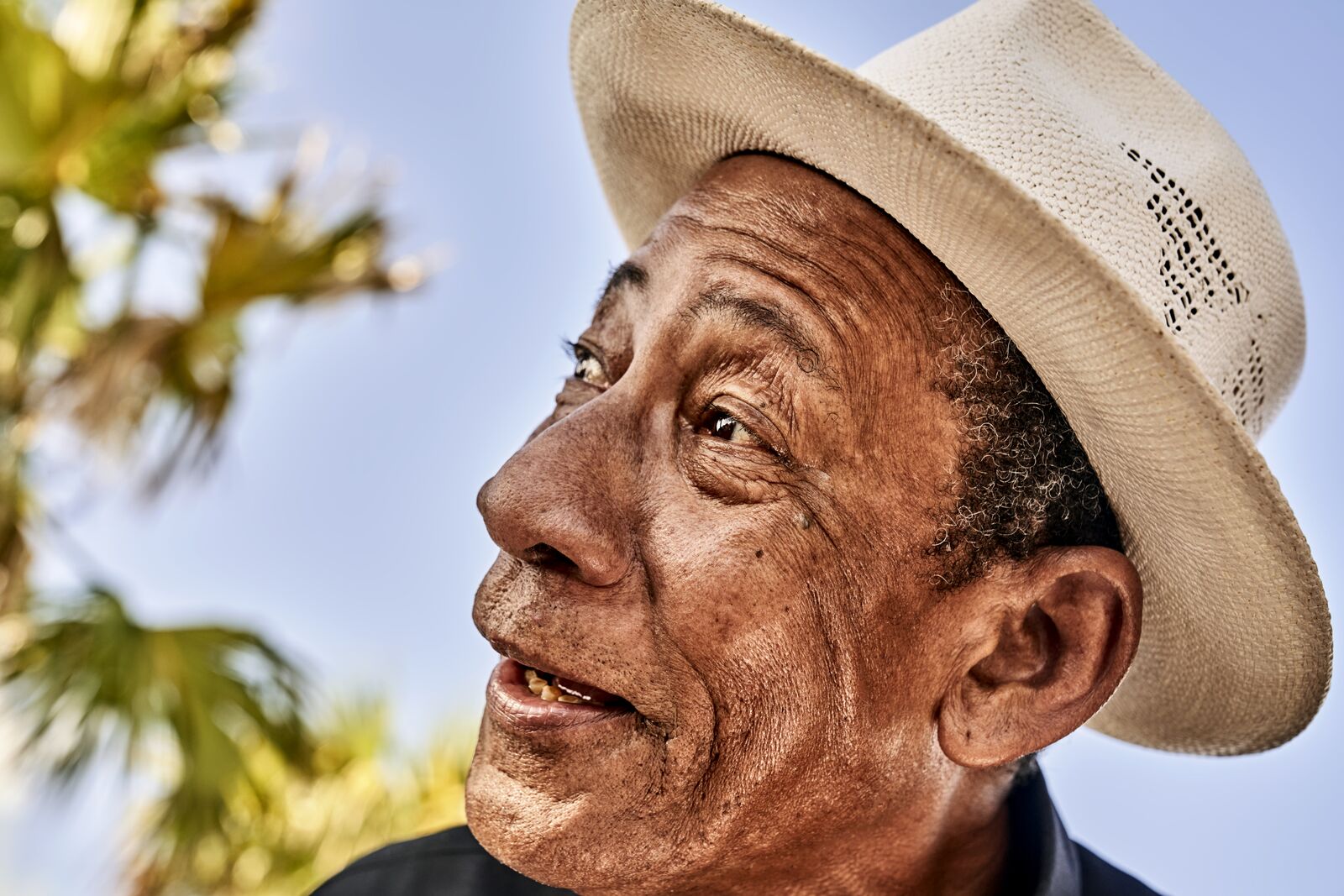 Person in a straw hat looking upward with a slight smile against a bright sky.