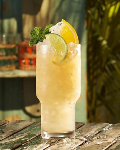 Mai Tai cocktail in tall glass with lime wedge, orange slice, mint sprig.