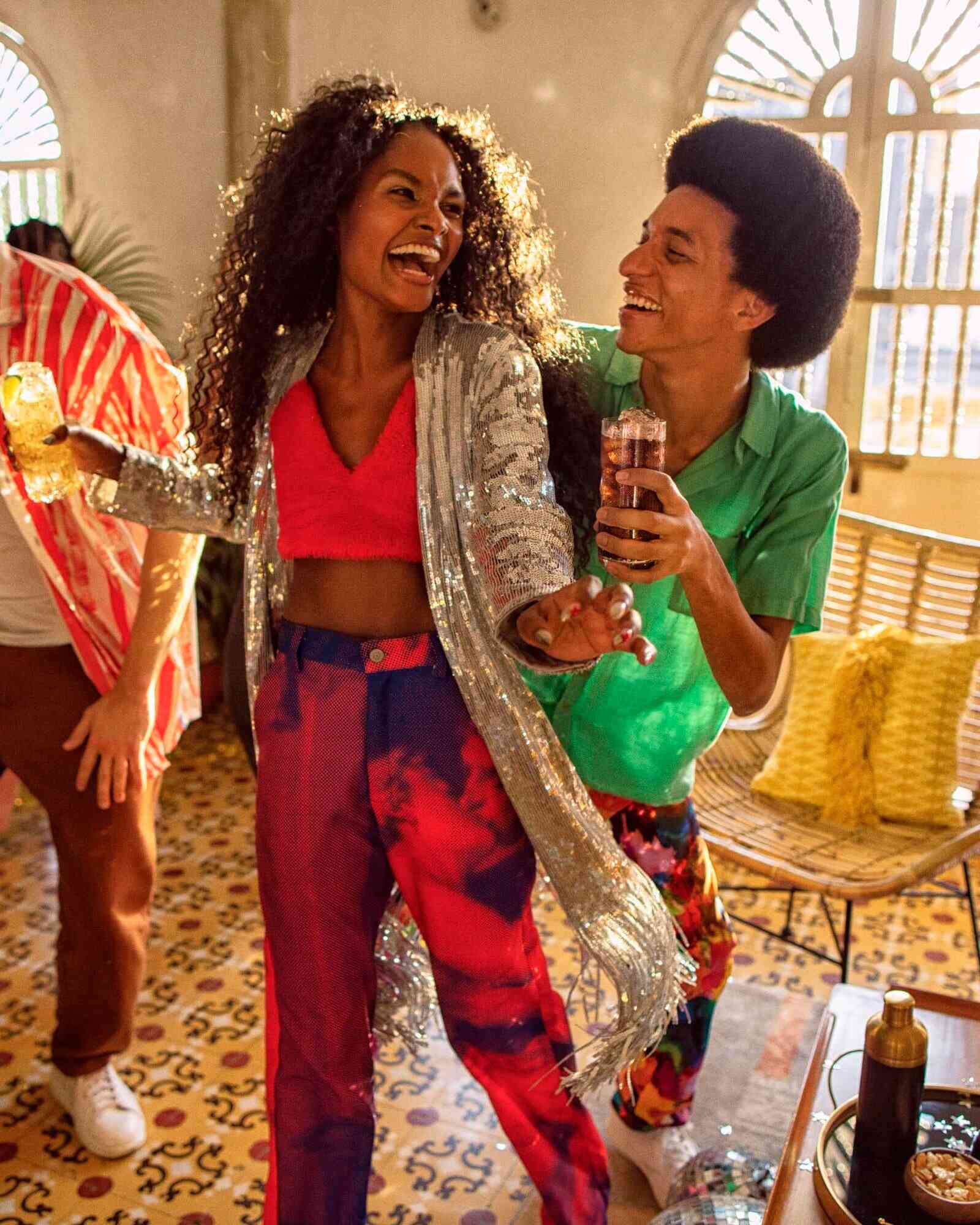 Two people dancing and holding cocktails in an energetic indoor setting.