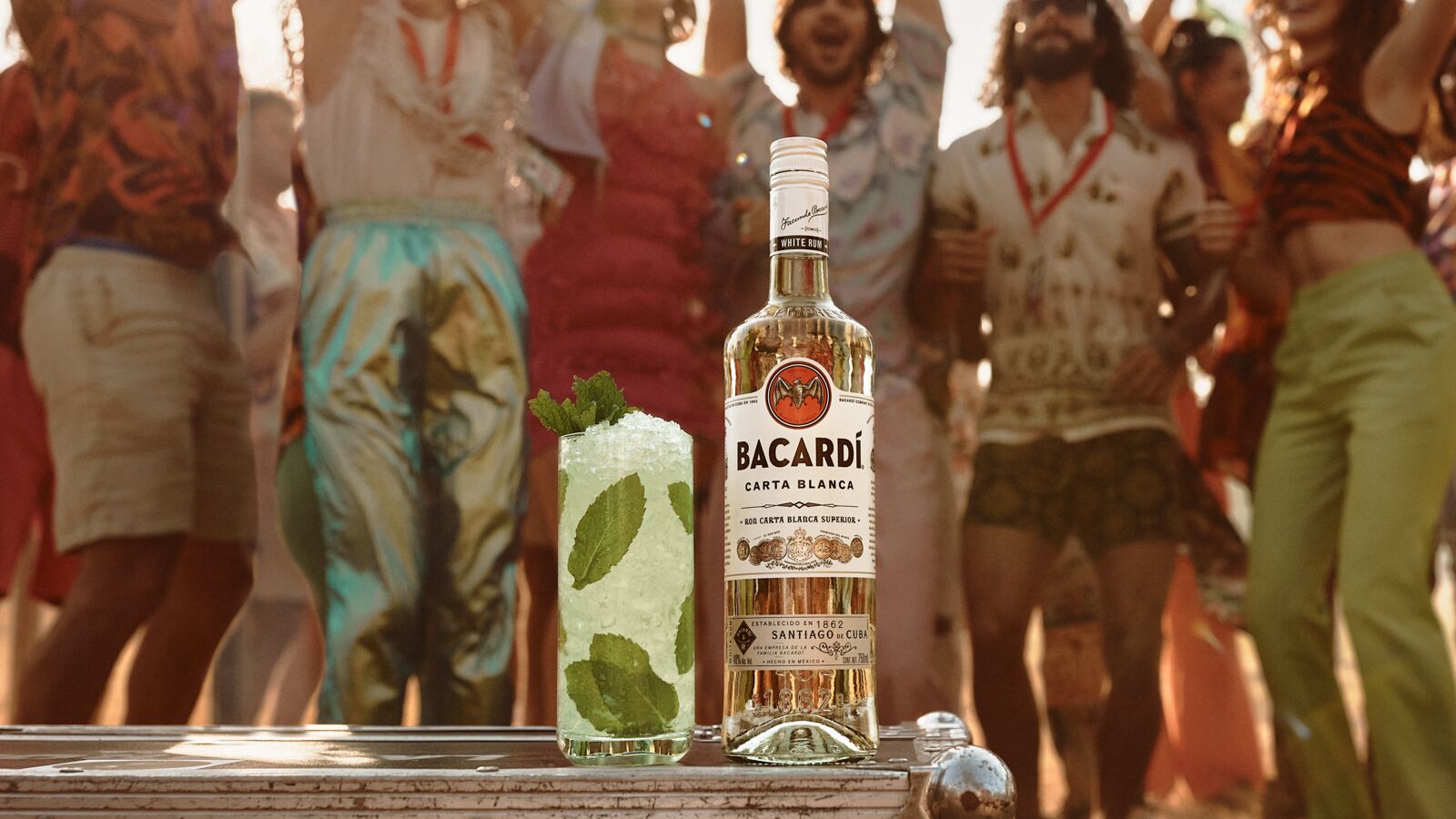 BACARDÍ Carta Blanca rum bottle beside a Mojito cocktail with mint leaves, ice.