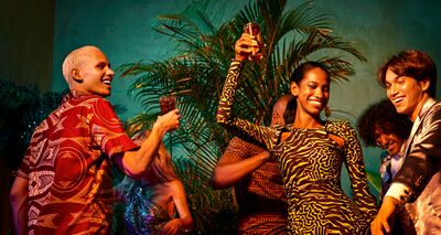 Group celebrating at a lively party with tropical foliage and warm lighting.